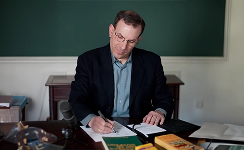 A man sitting at a table writing on paper.