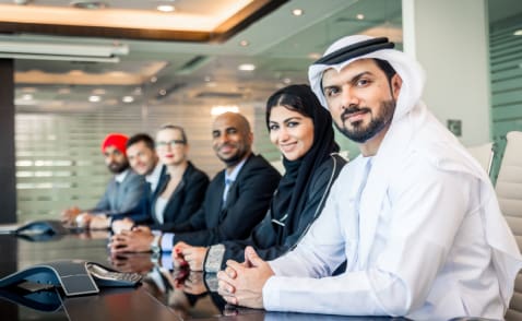 A group of people sitting at a table in front of a wall.